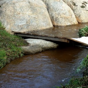 washout bridge caught on boulder in creek x.jpg