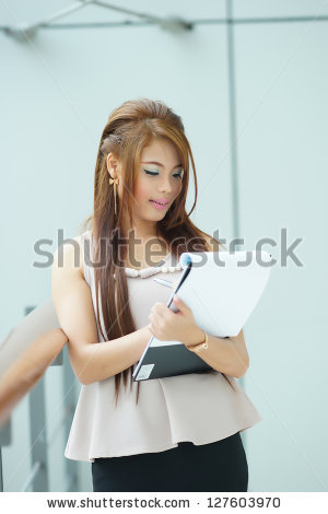 stock-photo-portrait-of-young-business-woman-standing-near-window-in-modern-office-and-writing-notes-127603970.jpg